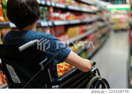 A person hand mobility issue is sitting in a wheelchair to shopping in a supermarket. 121559770