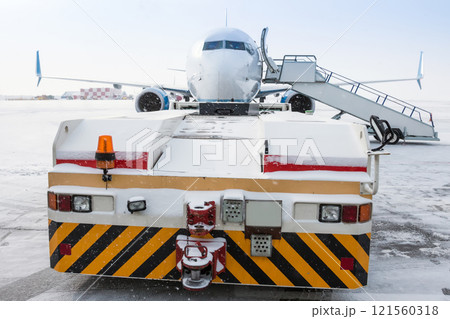Tow truck pulls up to the passenger airplane with boarding steps in a blizzard Tow truck pulls up to the passenger airplane with boarding steps in a blizzard 121560318