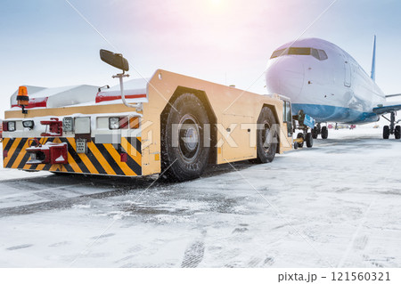 Tow tractor pushes the passenger aircraft at the cold winter airport apron 121560321
