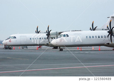Two white passenger turboprop aircrafts on the airport apron 121560489
