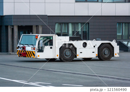 Airplane tow tractor at the airport apron near the terminal Airplane tow tractor at the airport apron near the terminal 121560490