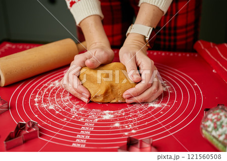 Hands kneading gingerbread dough on red mat 121560508