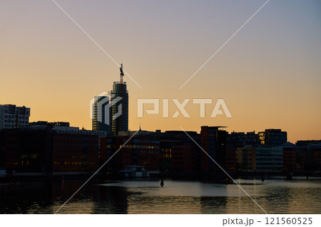 Cityscape with modern office building silhouettes along waterfront at sunset Cityscape with modern office building silhouettes along waterfront at sunset 121560525
