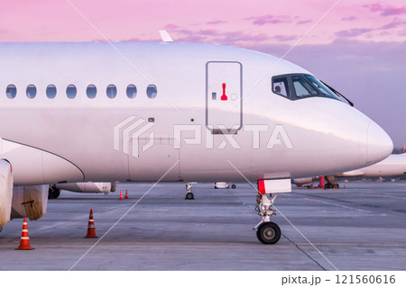 Front part of white modern passenger airliner on the morning airport apron Front part of white modern passenger airliner on the morning airport apron 121560616