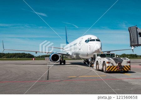 Tow truck pushes the passenger aircraft away from the boarding bridge Tow truck pushes the passenger aircraft away from the boarding bridge 121560658