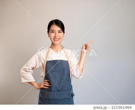 横を指差すエプロン姿の本人美女 横を指差すエプロン姿の本人美女 121561404