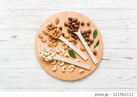 Assortment of nuts in wooden spoon on colored table. Cashew, hazelnuts, walnuts, almonds. Mix of nuts Top view with copy space 121562111
