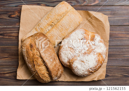 Assortment of freshly baked bread with napkin on rustic table top view. Healthy unleavened bread. French bread Assortment of freshly baked bread with napkin on rustic table top view. Healthy unleavened bread. French bread 121562155