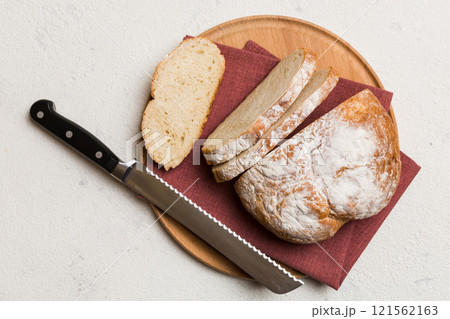Freshly baked bread cut with knife on a wooden board. top view Sliced bread and knife 121562163