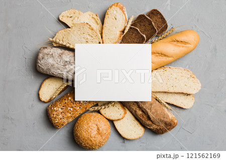 Minimalist paper blank mockup on background of Types of homemade bread. Different kinds of fresh bread as background, top view with space for your text or design Minimalist paper blank mockup on background of Types of homemade bread. Different kinds of fresh bread as background, top view with space for your text or design 121562169