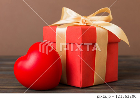 gift box with red bow and red heart on colored background. Perspective view. Flat lay 121562200