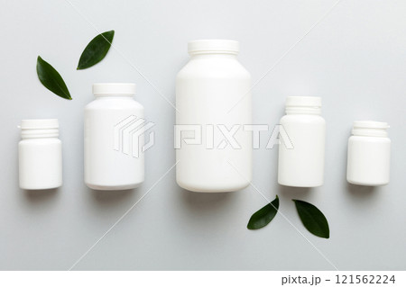 supplement pills with medicine bottle health care and medical top view. Vitamin tablets. Top view mockup bottle for pills and vitamins with green leaves, natural organic bio supplement, copy space 121562224