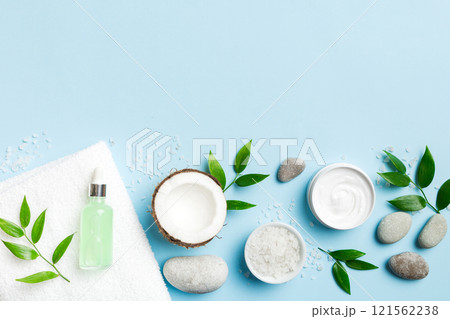 Coconut with jars of coconut oil and cosmetic cream on colored background. Top view. Free space for your text. Natural spa coconut cosmetics and organic treatment concept Coconut Spa composition 121562238