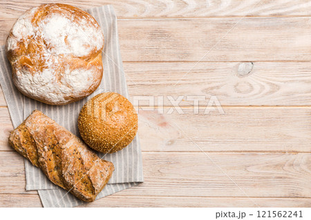 Assortment of freshly baked bread with napkin on rustic table top view. Healthy unleavened bread. French bread Assortment of freshly baked bread with napkin on rustic table top view. Healthy unleavened bread. French bread 121562241
