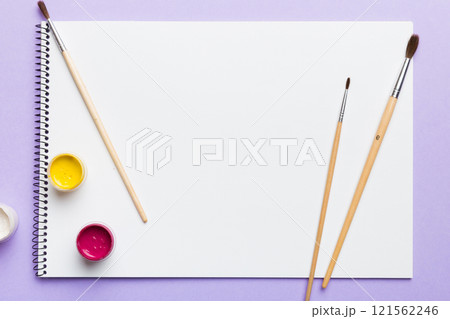 Album pages and paints, pencils, brush on a colored background. Top view with empty space. workplace for creativity. home teaching concept drawing Album pages and paints, pencils, brush on a colored background. Top view with empty space. workplace for creativity. home teaching concept drawing 121562246