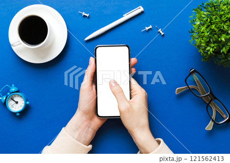 Top view of woman hands holding smart phone with blank copy space screen for your text message or information content. woman hand using phone white screen on top view 121562413