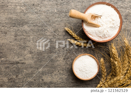 Flat lay of Wheat flour in wooden bowl with wheat spikelets on colored background. world wheat crisis Flat lay of Wheat flour in wooden bowl with wheat spikelets on colored background. world wheat crisis 121562529
