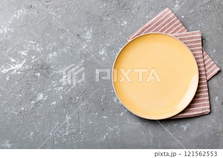 Top view on colored background empty round yellow plate on tablecloth for food. Empty dish on napkin with space for your design Top view on colored background empty round yellow plate on tablecloth for food. Empty dish on napkin with space for your design 121562553