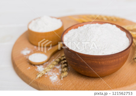 Flat lay of Wheat flour in wooden bowl with wheat spikelets on colored background. world wheat crisis Flat lay of Wheat flour in wooden bowl with wheat spikelets on colored background. world wheat crisis 121562753