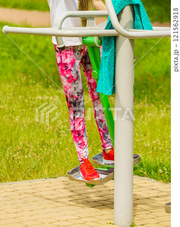 Girl doing legs exercises in outdoor gym 121562918