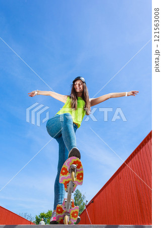 Teen girl skater riding skateboard on street. Teen girl skater riding skateboard on street. 121563008