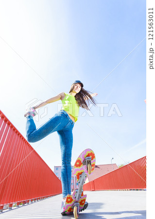 Teen girl skater riding skateboard on street. Teen girl skater riding skateboard on street. 121563011