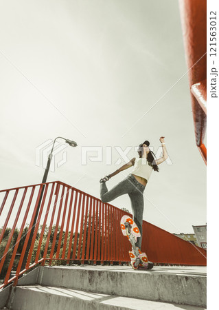 Teen girl skater riding skateboard on street. Teen girl skater riding skateboard on street. 121563012