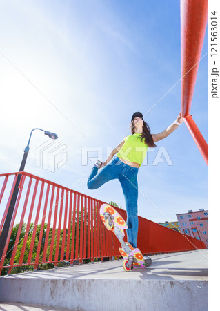 Teen girl skater riding skateboard on street. 121563014