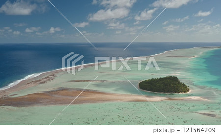 Aerial view of Tikehau island atoll in French Polynesia. Vibrant pink sand and turquoise lagoon, coral reef barrier, and blue ocean under cloudy sky. Remote wild nature paradise, exotic summer travel 121564209