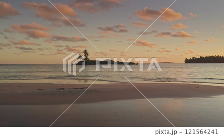 Breathtaking aerial flight over Tikehau island at sunset, vibrant pink sky, tranquil turquoise waters, lush palm trees, serene escape in heart of French Polynesia. Remote wild nature exotic paradise 121564241