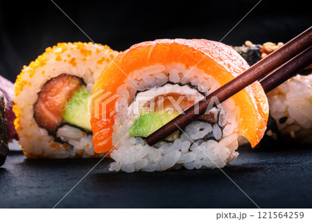 Sushi rolls on a black background. Uramaki with salmon and avocado Sushi rolls on a black background. Uramaki with salmon and avocado 121564259