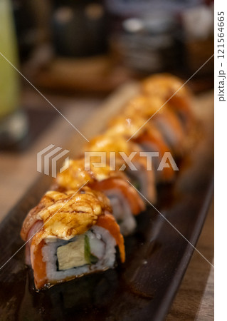Burned Salmon Sushi roll with cheese served on plate 121564665