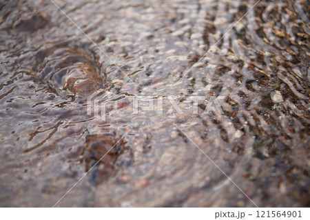 The camera captures a shallow stream of water flowing down the surface of the asphalt, forming small waves. Then it comes to a spring that bursts out of the ground, rising to the surface The camera captures a shallow stream of water flowing down the surface of the asphalt, forming small waves. Then it comes to a spring that bursts out of the ground, rising to the surface 121564901