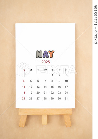 Calendar page for May 2025 with wood easel on old brown background. 121565166