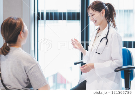 診察室で患者と会話する若い女性医師のイメージ 診察室で患者と会話する若い女性医師のイメージ 121565789