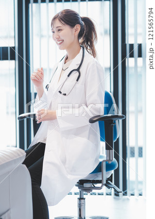 診察室で患者と会話する若い女性医師のイメージ 121565794