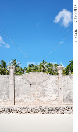 Old cracked concrete fence by a beach. 121565912