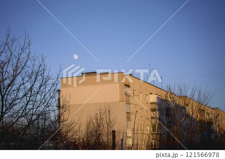 a full moon over paneled high-rise building at sunset 121566978