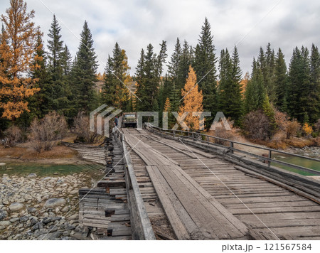 Old truck driving on a dilapidated bridge over a river. Old truck driving on a dilapidated bridge over a river. 121567584
