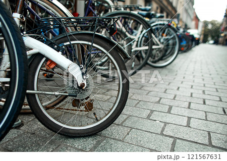 Close-up of a wheel in a row of parked bicycles on the streets of Europe. Close-up of a wheel in a row of parked bicycles on the streets of Europe. 121567631