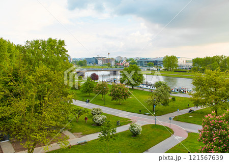 A cozy European park in the center of Krakow. Tourists walk and enjoy a summer evening in a lush park in Poland. A cozy European park in the center of Krakow. Tourists walk and enjoy a summer evening in a lush park in Poland. 121567639