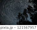 Star trails over a forest at night create a mesmerizing celestial display amidst towering trees 121567957