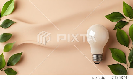 Light bulb adorned with fresh green leaves sits atop a neutral box, representing sustainability and modern design aesthetics 121568742