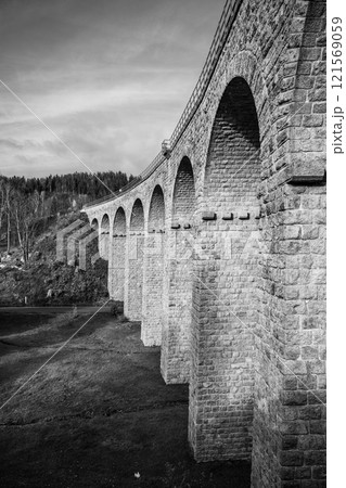 On a sunny autumn day, the impressive railway viaduct in Smrzovka stands majestically against the backdrop of the Jizera Mountains, showcasing stunning architecture and natural beauty. 121569059