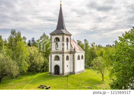 The Church of Saint John of Nepomuk stands proudly on Zvicina Hill, surrounded by lush greenery. Its distinct architecture is a highlight against the backdrop of a cloudy sky in Czechia. 121569317