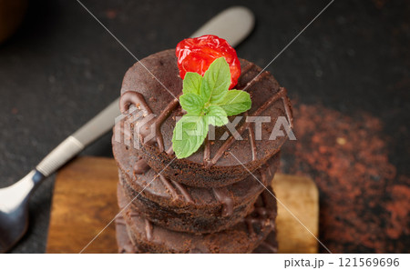 Chocolate brownies stacked, with the top adorned by a juicy red cherry and mint leaves Chocolate brownies stacked, with the top adorned by a juicy red cherry and mint leaves 121569696