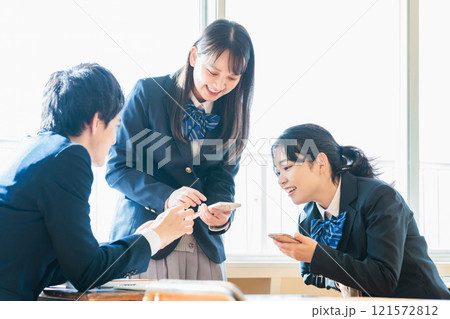 教室でクラスメイトとスマホを見ながら話す男女高校生 教室でクラスメイトとスマホを見ながら話す男女高校生 121572812
