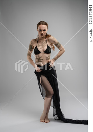 Model poses in stylish black attire against a plain gray background Model poses in stylish black attire against a plain gray background 121573941