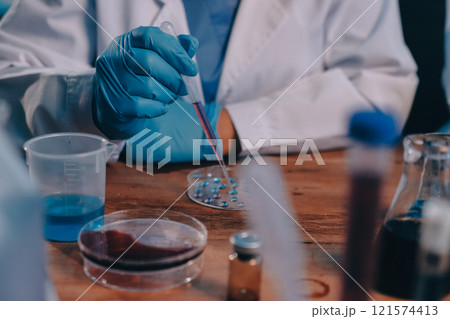 Blood test in the laboratory. Laboratory assistant working with the dispenser. Vacuum tubes with blood. 121574413