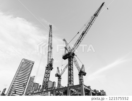 Black and white photo, Low-angle view of cranes and steel structures of building construction with a blue sky background in Taiwan. Black and white photo, Low-angle view of cranes and steel structures of building construction with a blue sky background in Taiwan. 121575552